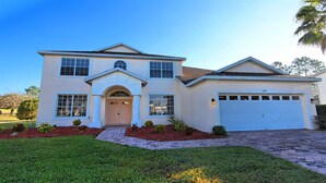 A two-story house with a central entrance, a garage, and a well-maintained lawn.