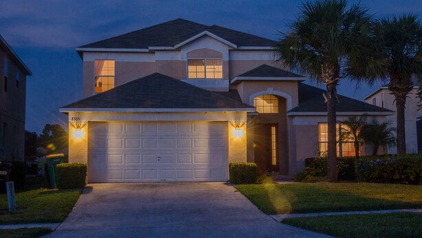 A two-story house with a garage, a covered driveway, and a well-maintained lawn with palm trees. - Ovm3553 - Emerald Island - 5 Bed 3 Baths Villa (Kissimmee)