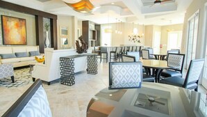 A spacious living area with a modern kitchen, dining area, and a large painting on the wall. - Ov3520 - Solterra Resort - 5 Bed 4.5 Baths Villa (Davenport)
