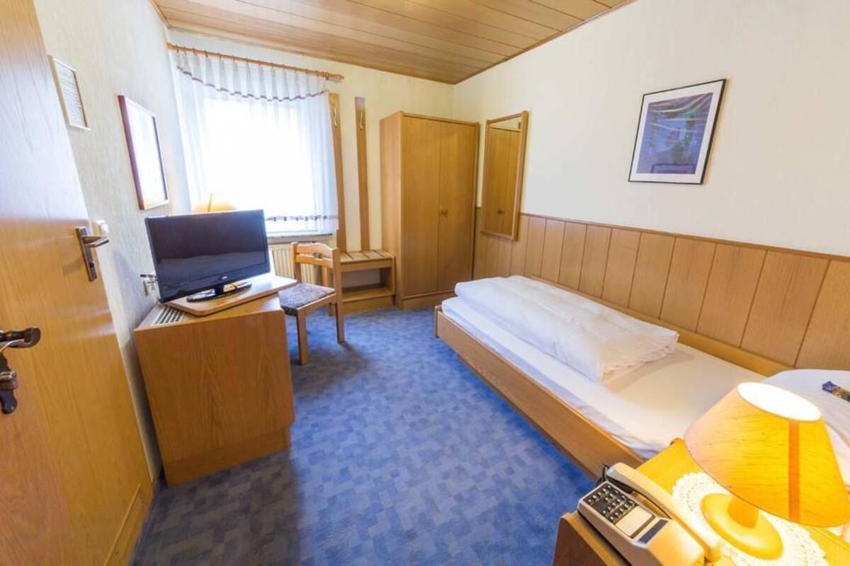 A hotel room with a bed, a desk with a computer, a TV, and a telephone.