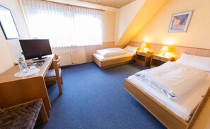 A hotel room with a bed, desk, chair, and a television.