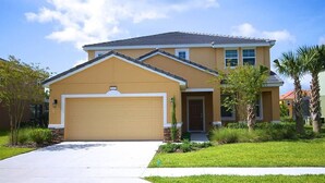 A two-story house with a garage, a front lawn, and a clear sky.
