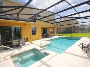 A pool area with a glass-enclosed patio, outdoor seating, and a view of the surrounding landscape.