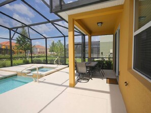A covered outdoor area with a pool, a table, and chairs.