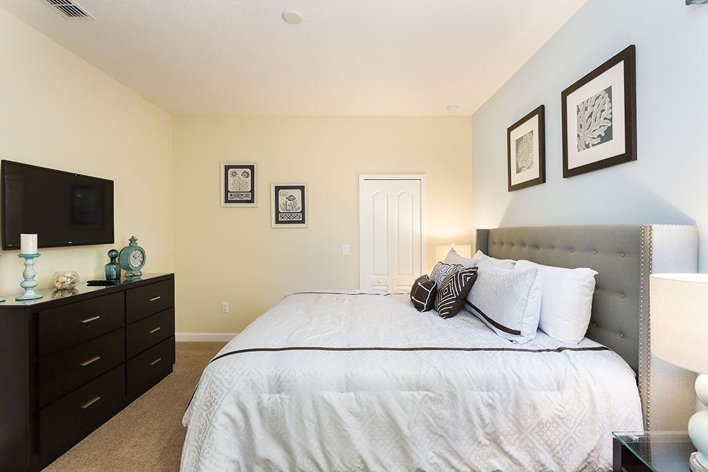 Une chambre à coucher avec un lit, une commode et un téléviseur fixé au mur.