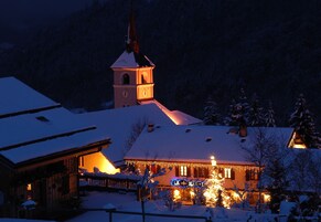 Un edificio cubierto de nieve con una torre iluminada y un cartel que dice "LA + TEA".