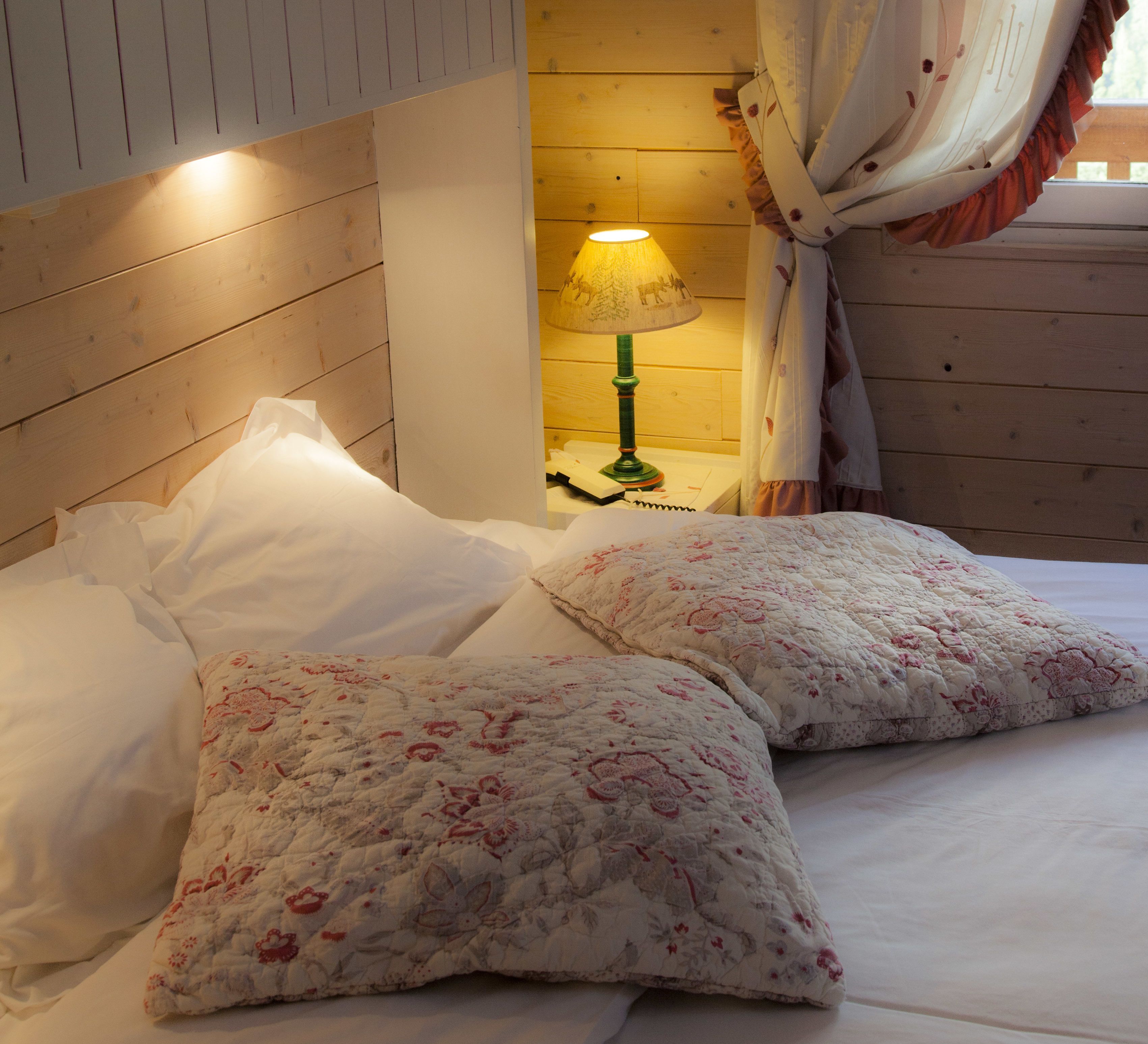 A bed with floral bedding, a bedside lamp, and a wooden headboard.