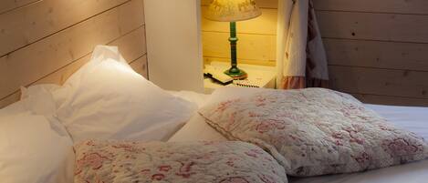 A bed with floral bedding, a bedside lamp, and a wooden headboard.