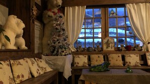 Une pièce chaleureuse avec un décor intérieur en bois, un sapin de Noël décoré et une fenêtre donnant sur un paysage enneigé.