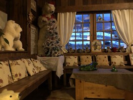 Una habitación acogedora con detalles de madera, un árbol de Navidad decorado y una ventana con vistas nevadas.