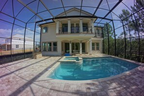 Ein zweigeschossiges Haus mit Swimmingpool, überdachter Terrasse und Blick auf Bäume.