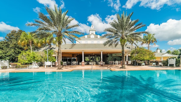 Un hôtel doté d’une piscine, de palmiers et d’un patio couvert.