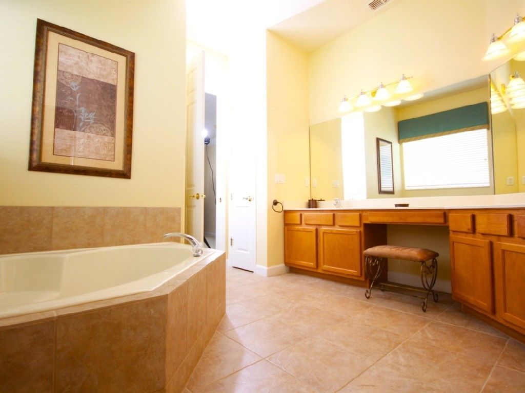 Ein Badezimmer mit einer Badewanne, Holzschränken und einem Waschtisch mit Spiegel.