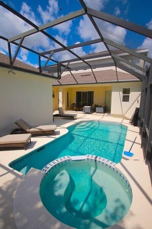 A swimming pool with lounge chairs, a covered patio, and a view of the backyard.