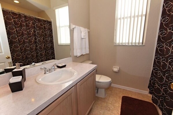 A bathroom with a sink, toilet, and a large mirror.
