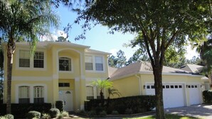 A two-story house with a garage, a well-maintained lawn, and mature trees. - Ov3141 - Highlands Reserve - 6 Bed 4 Baths Villa (Davenport)