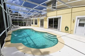En swimmingpool med en glasvägg runt om, omgiven av en uteplats med trappsteg som leder ner till poolen.