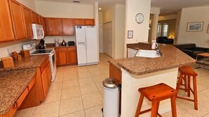 A kitchen with wooden cabinets, granite countertops, a microwave, a refrigerator, a sink, and a trash can. - Ov3141 - Highlands Reserve - 6 Bed 4 Baths Villa (Davenport)
