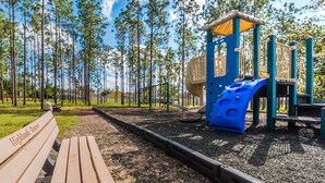 Leikkikentällä on liukumäki ja kiipeilytelineitä, ja se on ympäröity metsäisellä alueella sekä siellä on myös penkki.