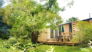 A wooden cabin with a deck, a table, and chairs. - Moulin des Sandaux Natur'park (Saint-Andre-et-Appelles)