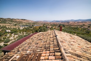 A terracotta-tiled roof with a red roof edge, overlooking a valley with terraced fields and a distant body of water. - Principe di Aragona (Aragona)