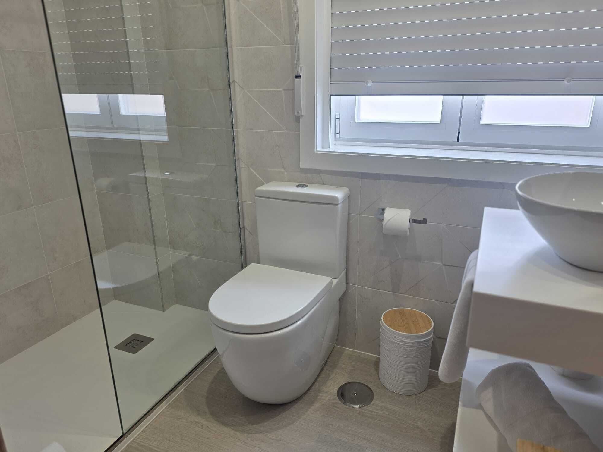 A modern bathroom with a glass shower enclosure, a toilet, a bidet, and a sink.