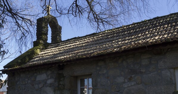 A stone building with a tiled roof and a chimney. - Hotel O Pazo (Vigo)