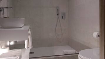 Un baño moderno con cabina de ducha de vidrio, un lavabo blanco y un inodoro.