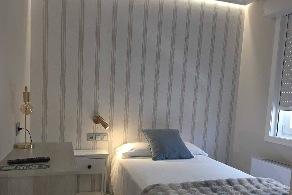 A bedroom with a bed, bedside tables, a lamp, and a window.