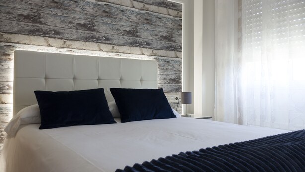 A modern hotel room with a large bed, a wooden headboard, and a nightstand with a lamp. - Hotel O Pazo (Vigo)