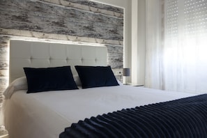A modern hotel room with a large bed, a wooden headboard, and a nightstand with a lamp. - Hotel O Pazo (Vigo)
