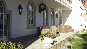 A building with a balcony adorned with greenery and red decorations, arched windows, and outdoor seating. - Hotel O Pazo (Vigo)