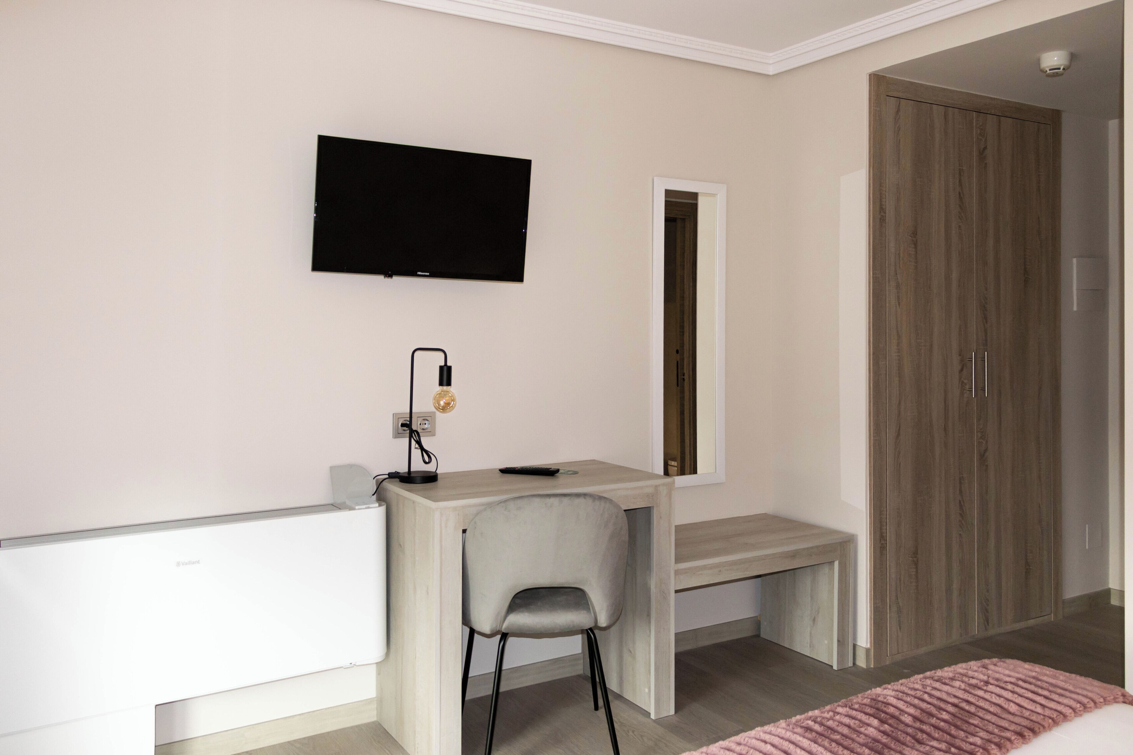 A modern room with a desk, chair, television, and wardrobe.