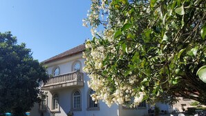 A two-story building with a balcony, surrounded by a grassy lawn and white outdoor furniture. - Hotel O Pazo (Vigo)