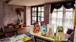 A room with a dining table, chairs, a potted plant, and a window with curtains. - Guest House Vijecnica (Sarajevo)
