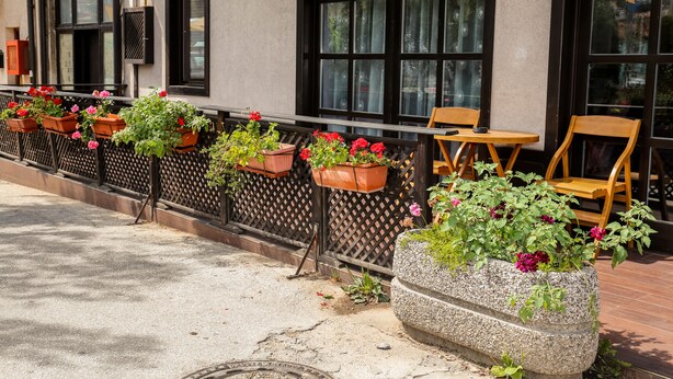 A row of outdoor seating with potted plants and a stone planter. - Guest House Vijecnica (Sarajevo)