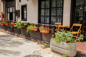 A row of outdoor seating with potted plants and a stone planter. - Guest House Vijecnica (Sarajevo)