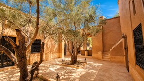 Un patio exterior con árboles, una escalera y un edificio de tejado con tejas.