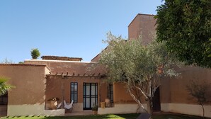 A poolside area with lounge chairs and a small garden. - Tagadert Lodge (Tameslouht)