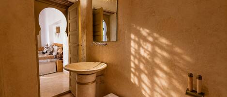 A bathroom with a pedestal sink, a mirror, and a towel rack.