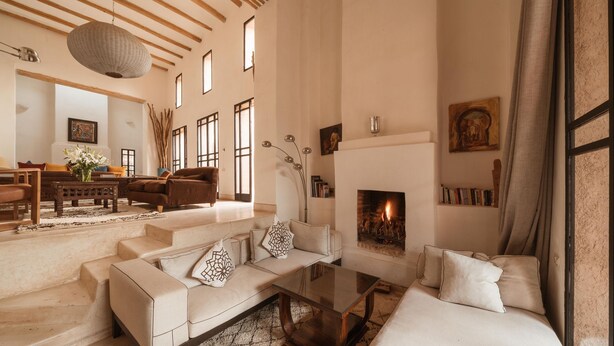 A spacious living room with a fireplace, a sofa set, a coffee table, and a bookshelf. - Tagadert Lodge (Tameslouht)