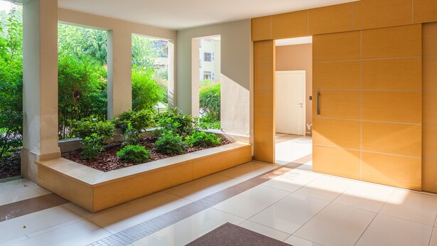 Un interior moderno con una planta central, ventanas amplias y piso de baldosas.