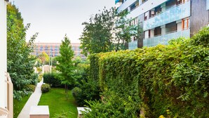 Un patio con un sendero, abundante vegetación y edificios modernos al fondo.
