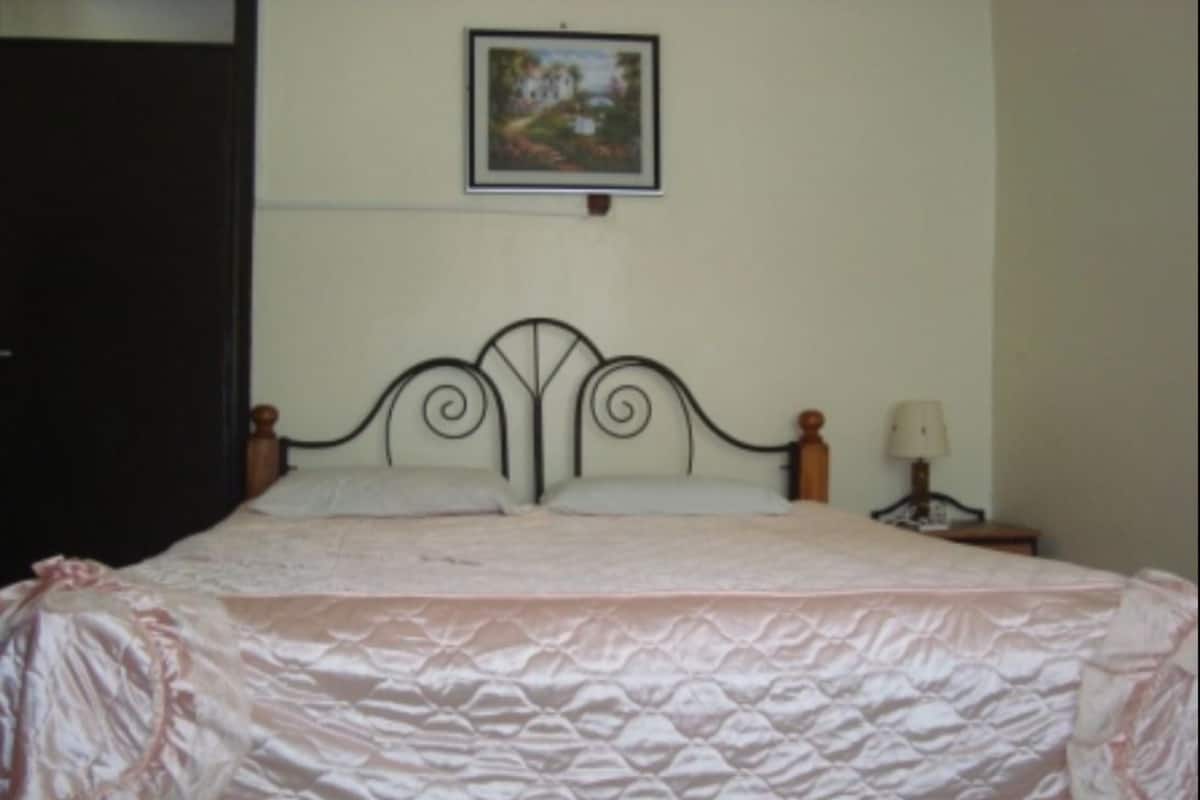A neatly made bed with a pink bedspread and a headboard with a decorative design.