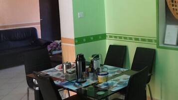 Un comedor con una mesa dispuesta para cuatro personas, sillas, una cesta en la pared y certificados enmarcados.