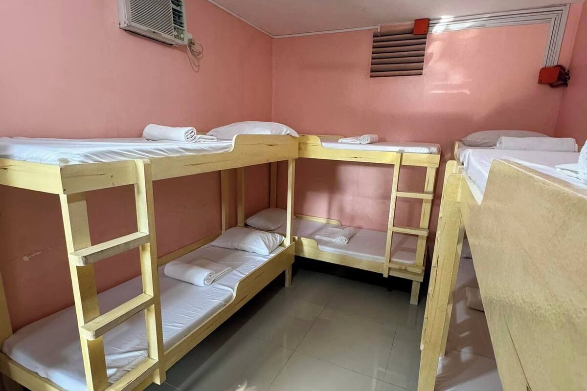 Una habitación con literas, ventilador de techo y ventana con persianas.