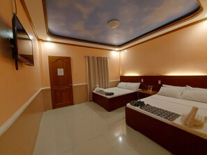 A hotel room with two beds, a ceiling with a cloud design, a flat-screen TV, and a door with a sign. - New Village Lodge (Oslob)