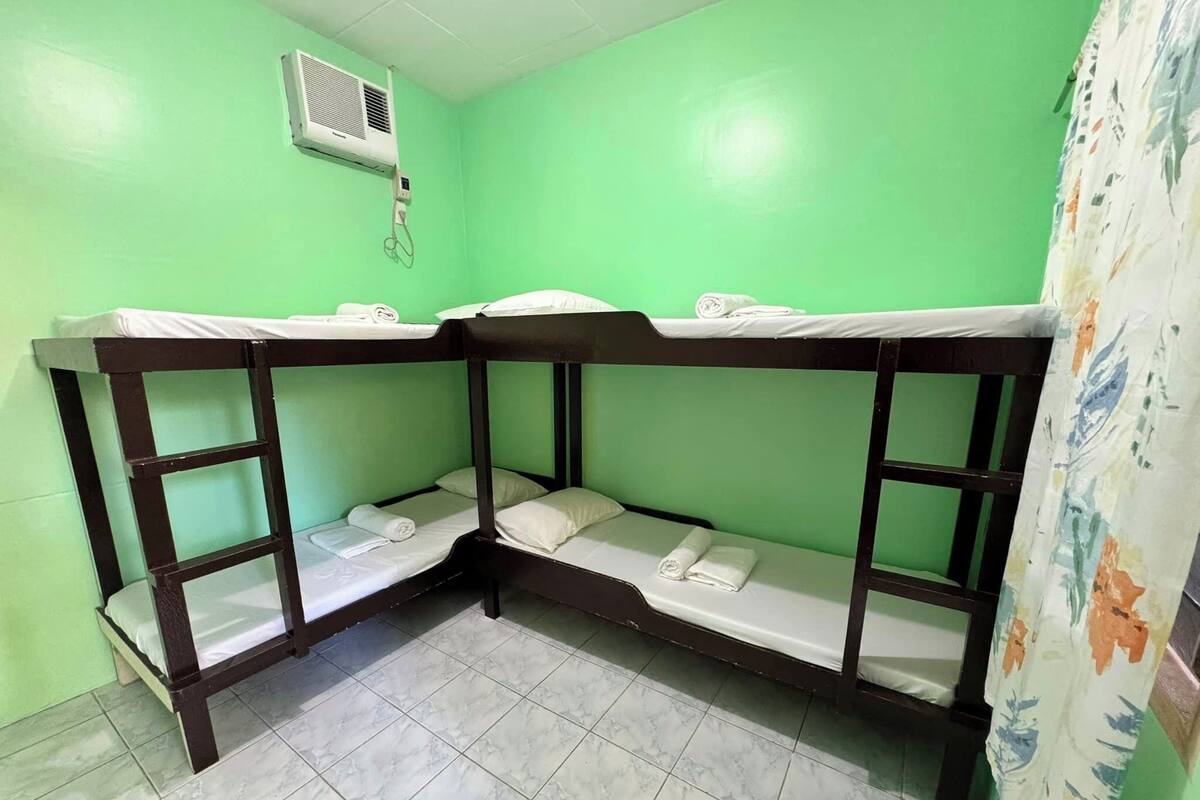 Una habitación con literas, piso de baldosas y pared verde.