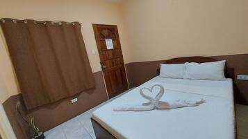 Una habitación de hotel con una cama, una cortina marrón, una puerta de madera y una planta en maceta.