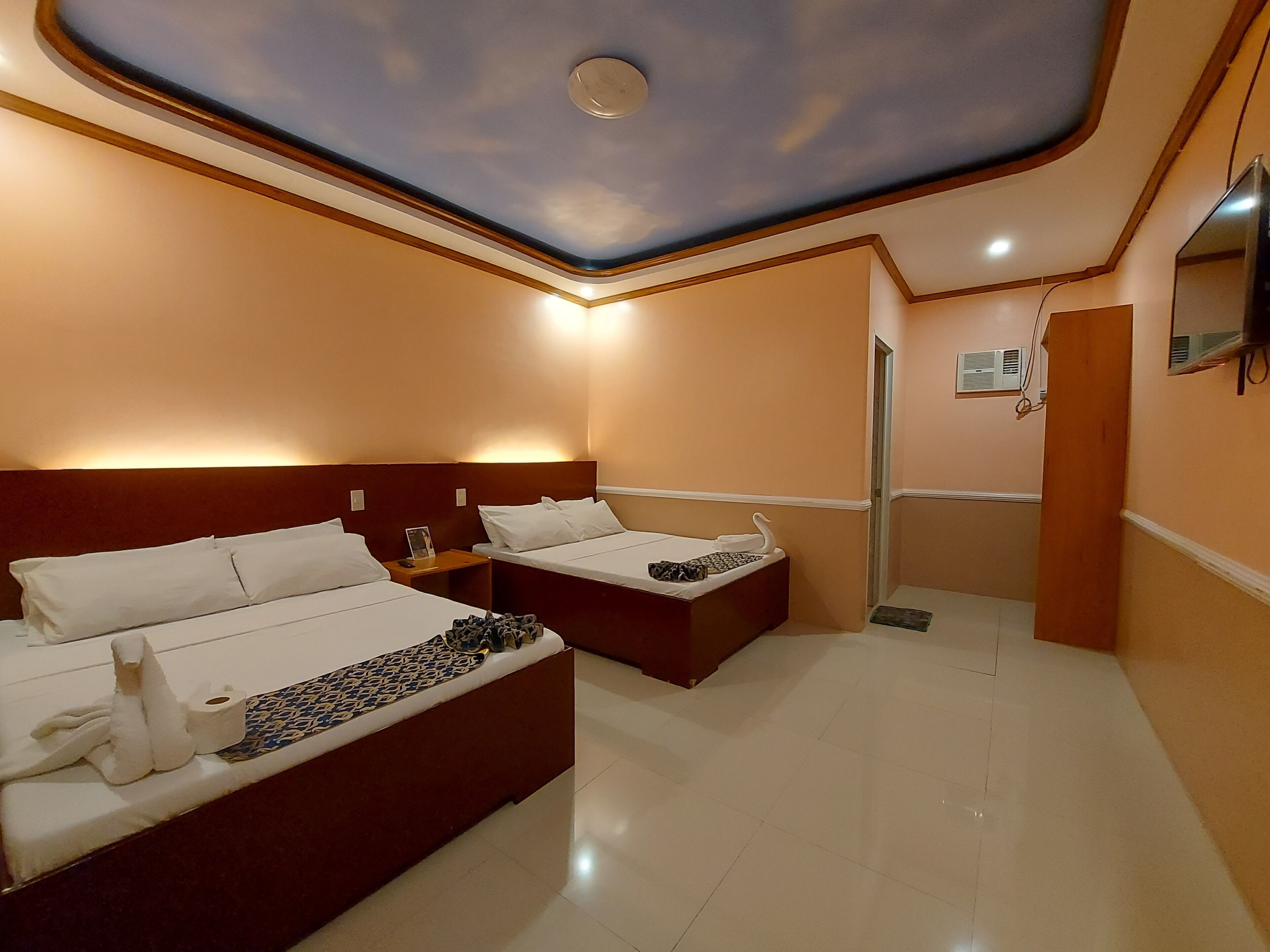 Habitación de hotel con dos camas, ducha y un techo con luz empotrada.